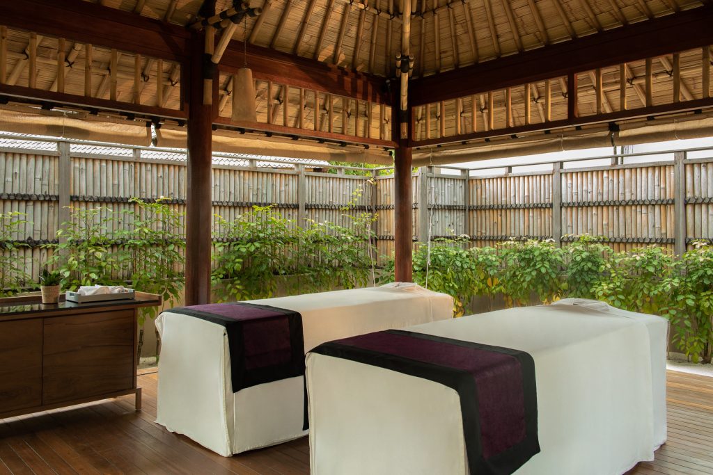 Offener Wellness Spa Raum mit zwei Massageliegen, Bambuswänden und Holzmöbeln im Dhawa Ihuru auf den