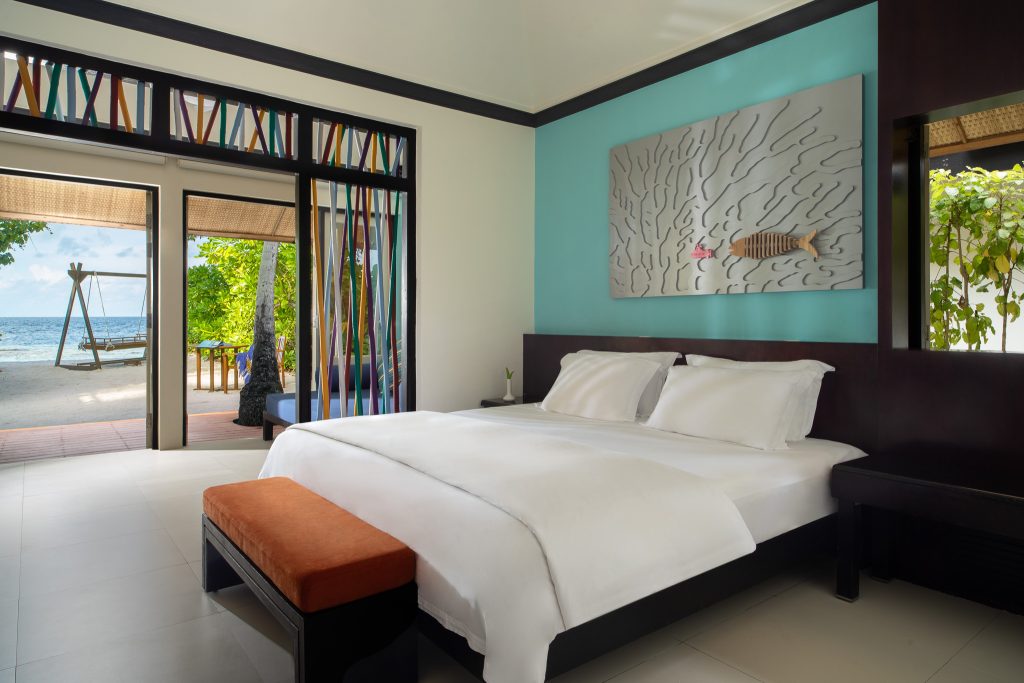 Modernes Hotelzimmer der Beachfront Jet Pool Villa mit großem Bett, Terrassentüren und Blick auf das Meer auf den