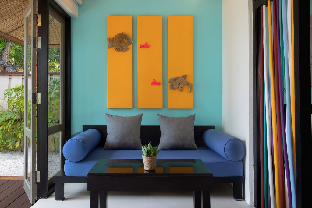 Moderne Sitzecke in Dhawa Ihuru Beachfront Rainmist Villa mit türkisfarbener Wand und gelben Holzpaneelen