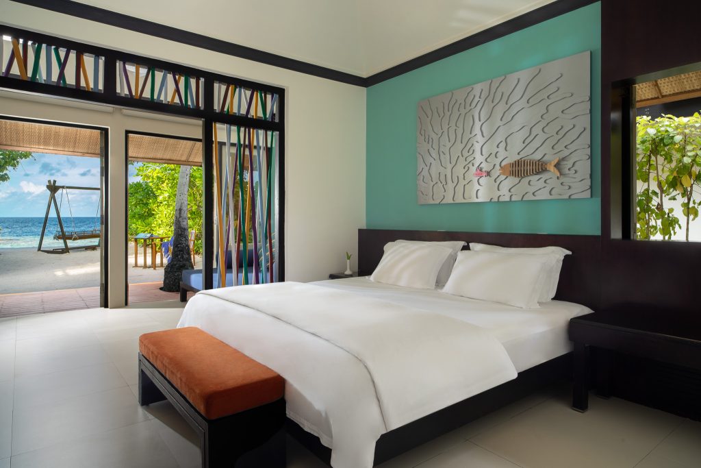 Hell eingerichtetes Zimmer der Beachfront Rainmist Villa mit großem Bett, türkisfarbener Wand und Meerblick von der Terrasse