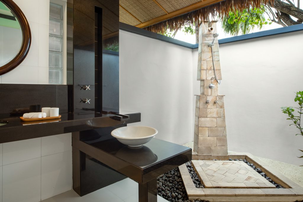 Offenes Badezimmer der Beachfront Villa im Dhawa Ihuru mit schwarzem Steinwaschtisch und steinerner Außendusche