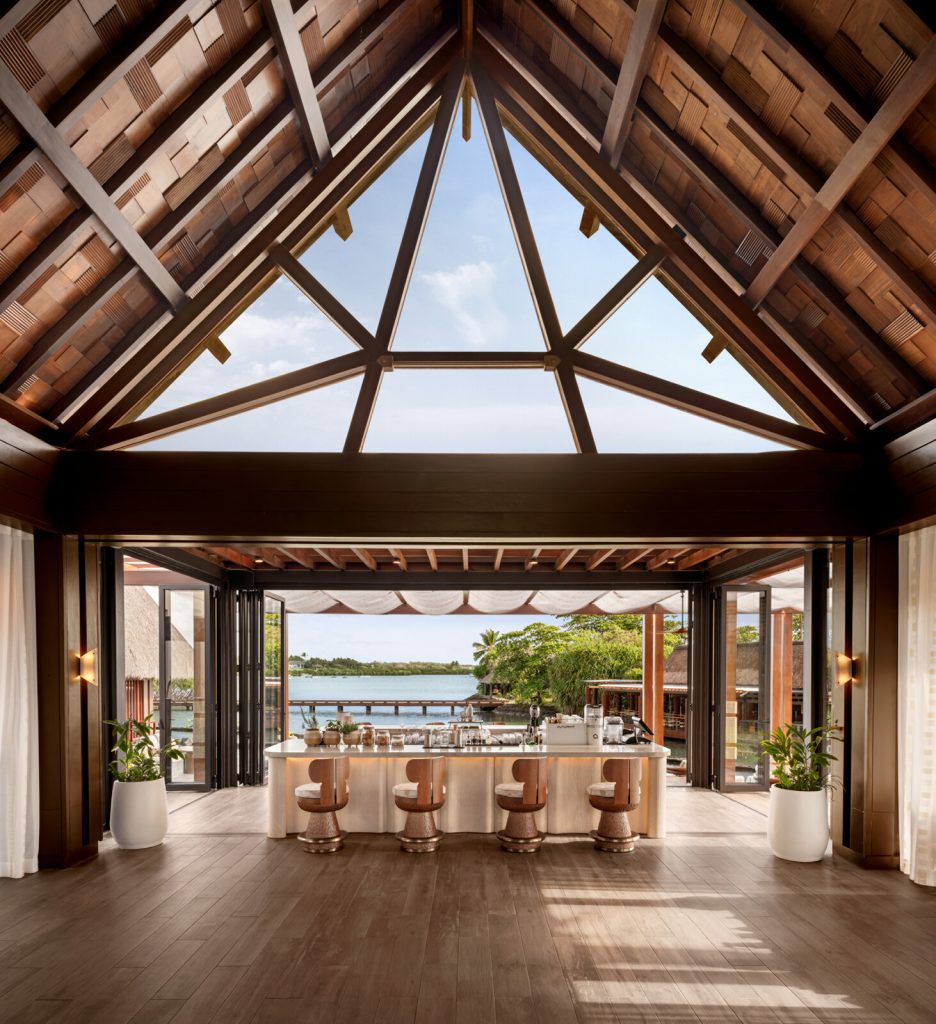 Offene Hotelbar mit hoher dreieckiger Holzdecke, Holz- und Glasmaterialien, Blick auf Grün