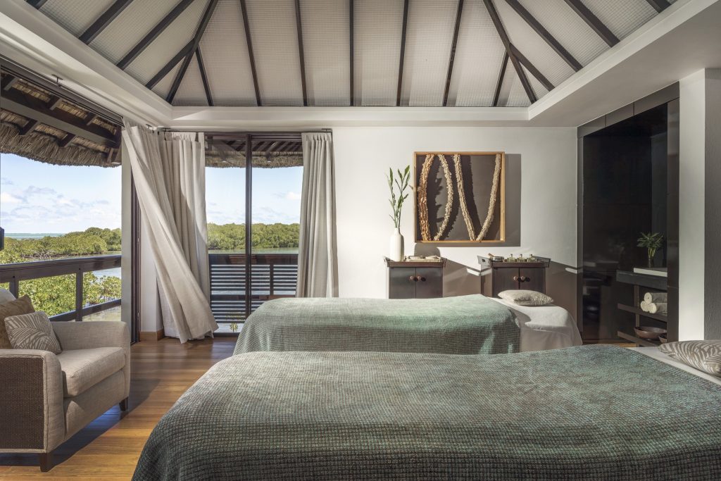 Helles Wellness-Spa-Zimmer mit zwei Massagetischen, großen Fenstern und Holzbalkendecke im Four Seasons Resort Mauritius At.