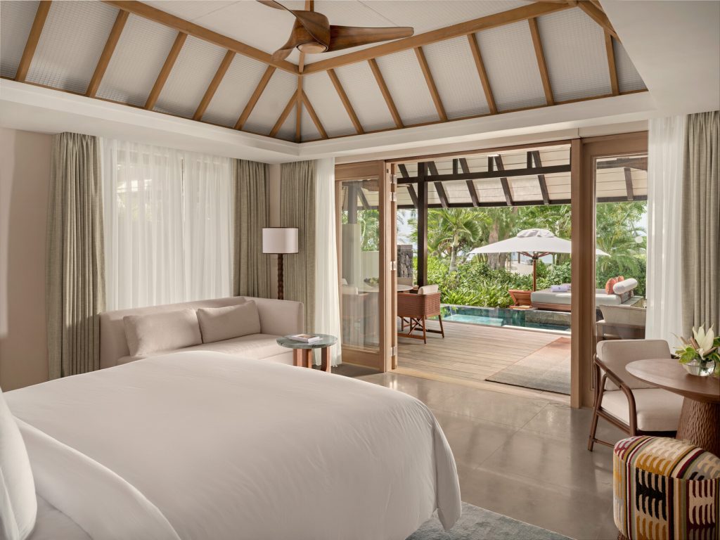 Zimmer mit großem Bett, beiger Couch, Holzdecke und Terrasse mit Holzdeck und kleinem Pool