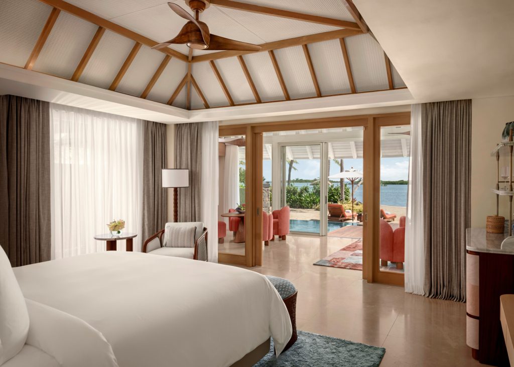 Hotelzimmer mit großem weißen Bett, Holzbalken, Ventilator, Terrasse mit Pool und Meerblick
