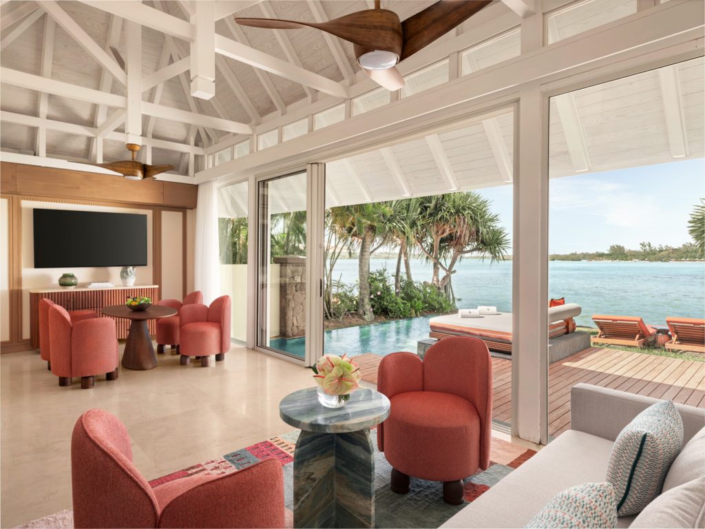 Helles Zimmer im Four Seasons Resort Mauritius At Anahita mit Holzdecke, Terrakotta Sesseln und Blick auf Terrasse.