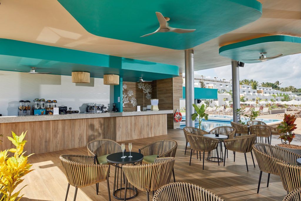Offene Bar im Hotel Riu Jambo mit Rattanmöbeln, hellem Holz, türkis-weißen Wänden und Poolbereich in Sansibar