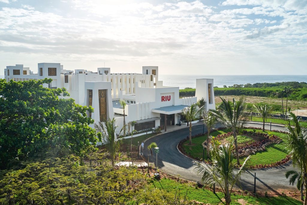 Hotel Riu Jambo mit weißer Fassade, geometrischen Mustern, umgeben von Grün und Palmen am Meer in Sansibar