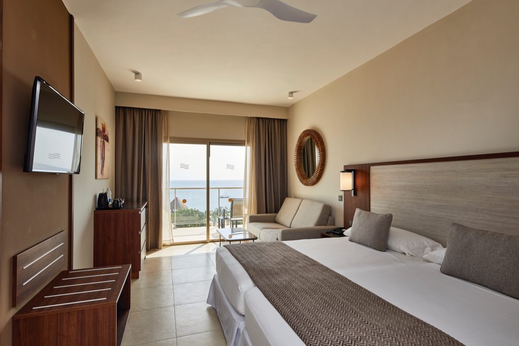 Modernes Hotelzimmer im Hotel Riu Jambo mit Doppelbett, Holzelementen und Meerblick vom Balkon in Sansibar