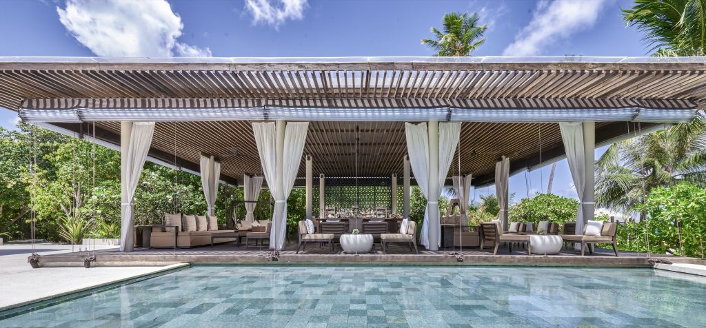 Offene Bar The Bar mit Holzüberdachung, beigen Sofas, weißen Vorhängen und Swimmingpool im Park Hyatt Maldives Hadahaa
