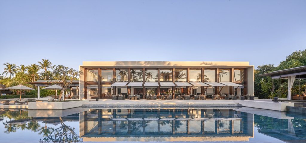 Modernes Hotelrestaurant mit großer Glasfront, Holzakzenten und Pool auf den