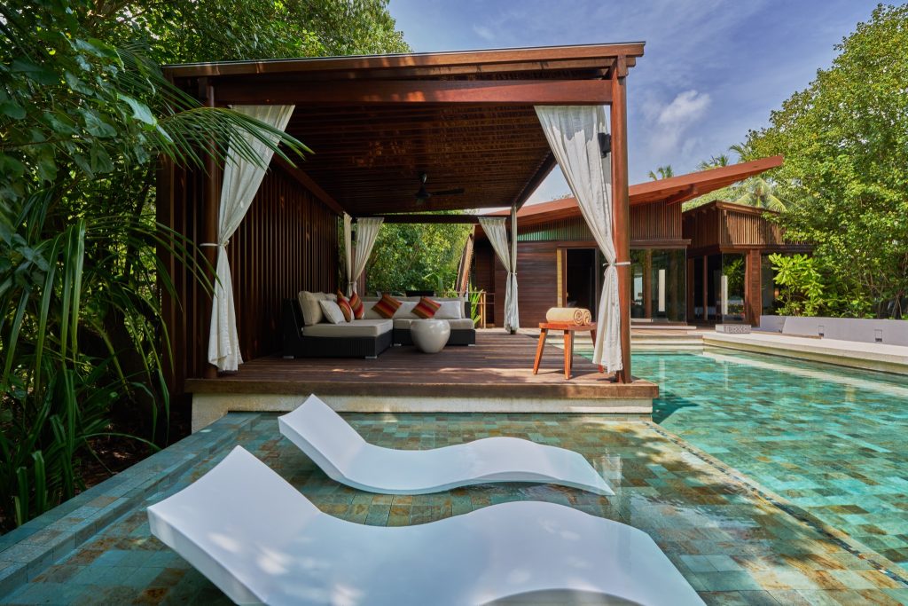 Terrasse der 2 Bedroom Beach Pool Villa im Park Hyatt Maldives Hadahaa mit Sofa, Vorhängen und Liegestühlen im Pool