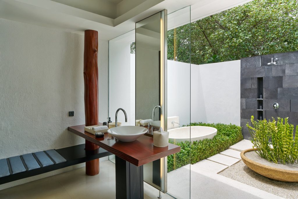 Badezimmer mit dunklem Holzwaschtisch, freistehender Badewanne und Außendusche in Deluxe Beach Pool Villa