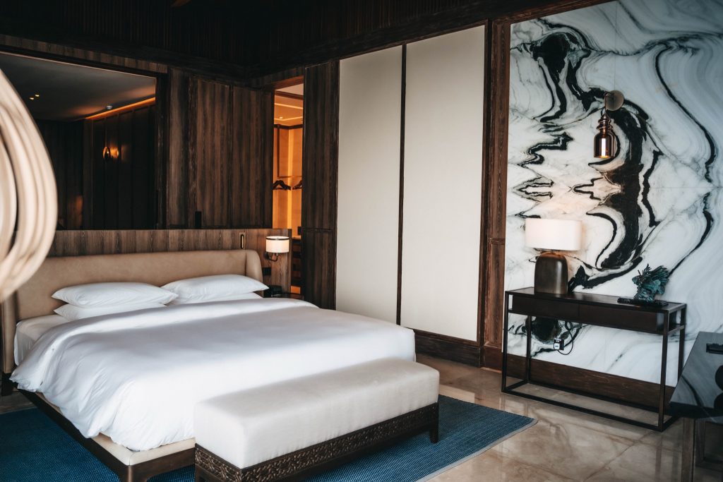 Zimmer der Kiaali Residence im Park Hyatt Maldives Hadahaa mit großem weißen Bett, Marmorwand und blauem Teppich