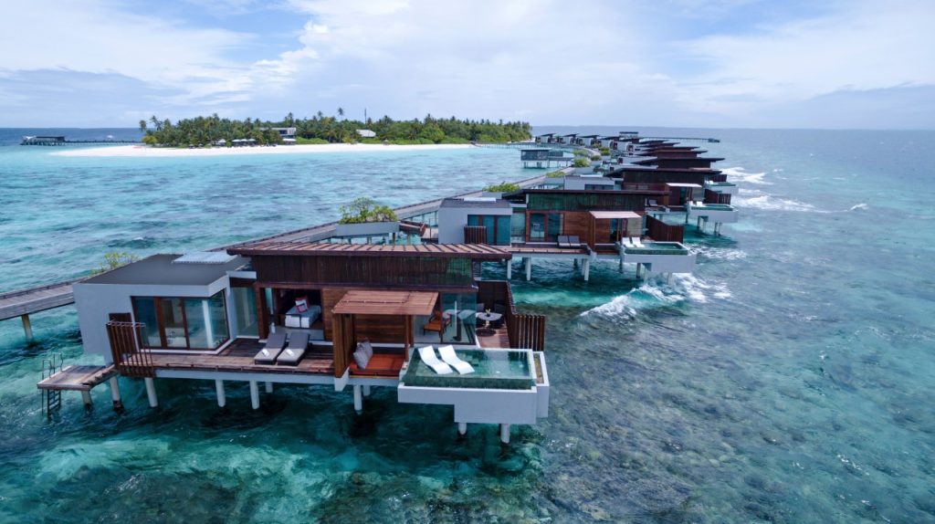 Reihe von Wasserbungalows aus Holz und Glas mit privaten Terrassen und kleinen Pools über dem türkisfarbenen Meer
