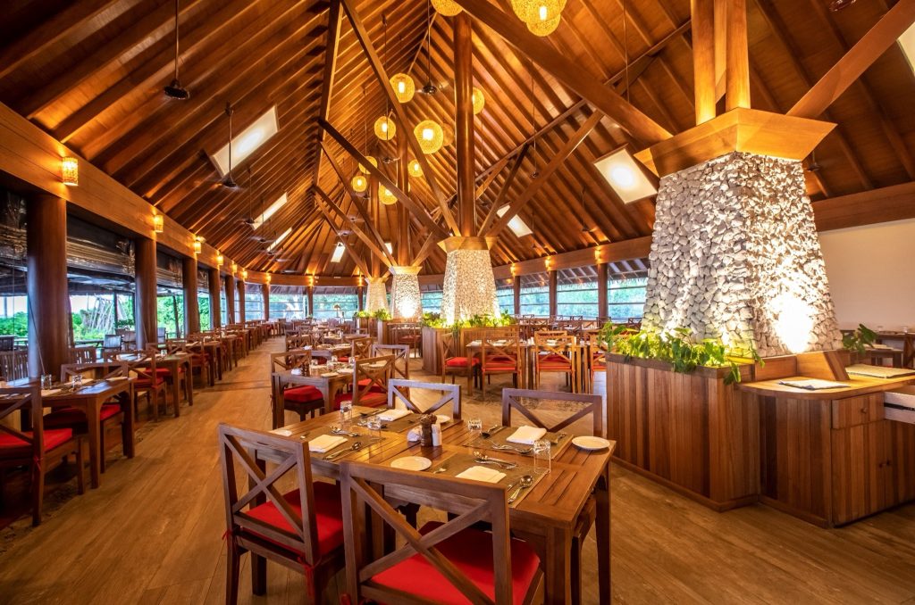 Restaurant Vakaru im Reethi Faru Resort mit hoher Holzdecke, Holztischen, roten Sitzpolstern