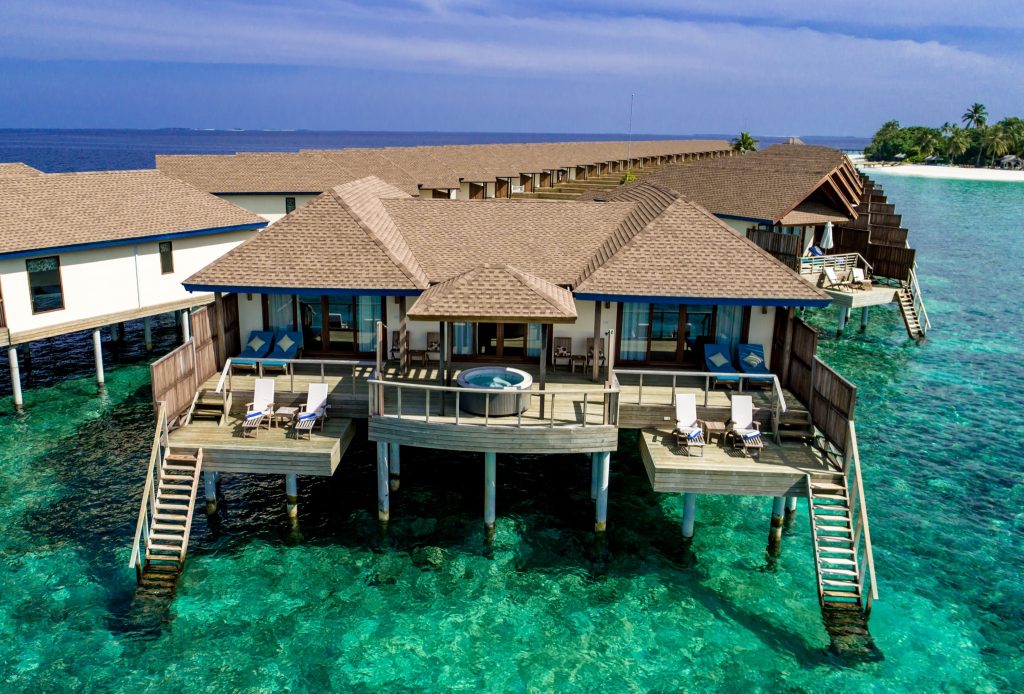 Reihe von Überwasser-Bungalows mit hellbraunen Schindeldächern und Holzterrassen mit Jacuzzi im türkisfarbenen Wasser