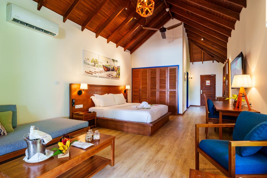 Hotelzimmer Deluxe 2BR Beach Suite mit Holzmöbeln, großem Bett, blauen Stühlen und Küstenbildern an der Wand