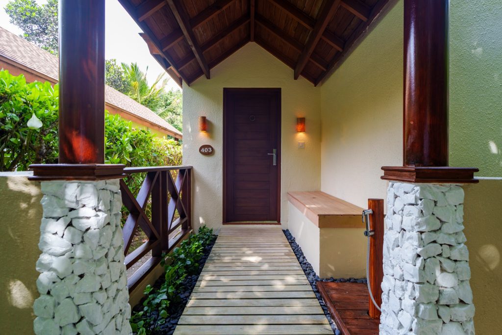 Eingangsbereich der Deluxe Beach Pool Villa im Reethi Faru Resort mit Holztür 403 und Holzsteg