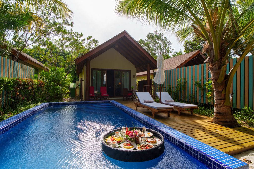 Außenbereich der Deluxe Beach Pool Villa im Reethi Faru Resort mit privatem Pool, Tablett mit Speisen auf Wasser, Holzdach.