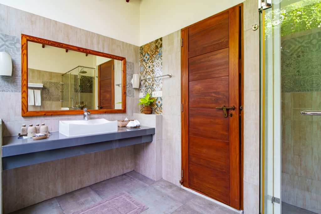 Modernes Badezimmer der Garden Villa im Reethi Faru Resort mit Waschbecken, rechteckigem Spiegel und Dusche