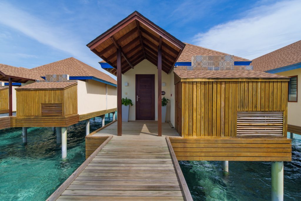 Water Villa im Reethi Faru Resort auf Stelzen über türkisblauer Lagune mit Holzschindeldach und hölzerner Promenade