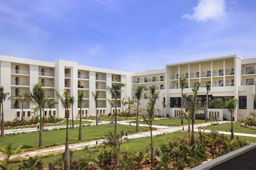 Mehrstöckiges Hotel Riu Palace Swahili mit weißer Fassade, symmetrischen Palmen und gepflegtem Garten in Sansibar