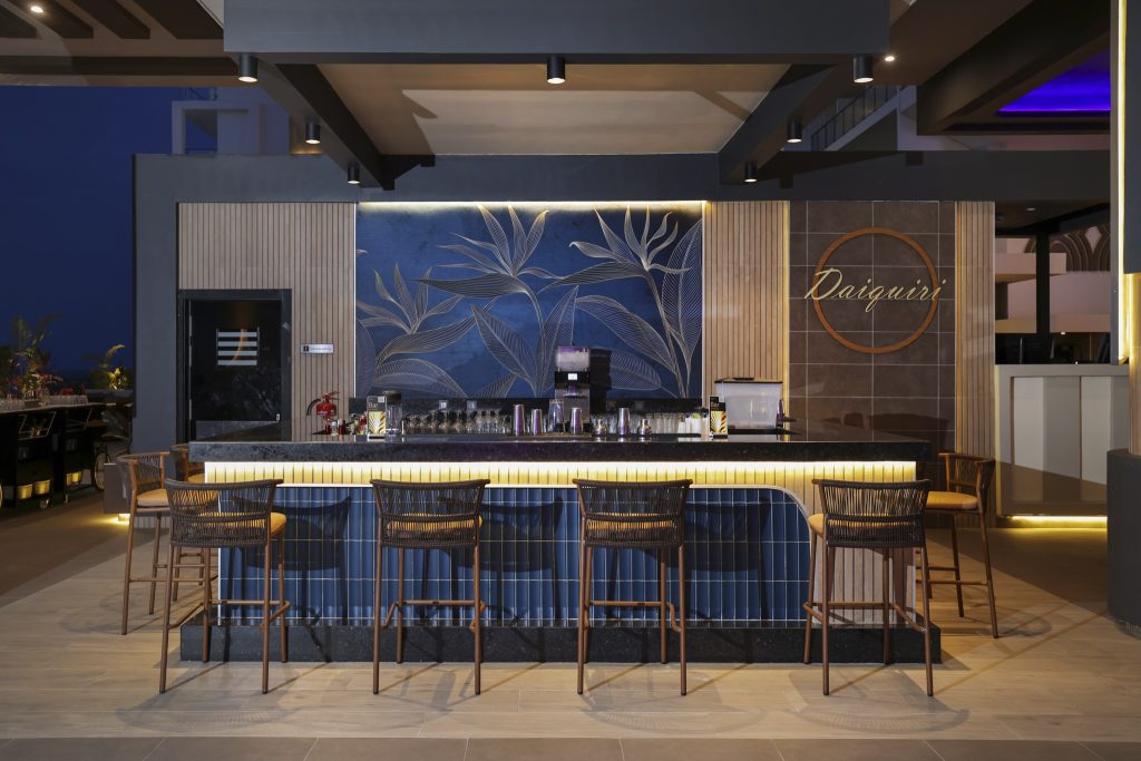Bar im Hotel Riu Palace Swahili mit dunkelblauer Fliesenfront, Holz-Barhockern mit Korbgeflecht und warmer Beleuchtung