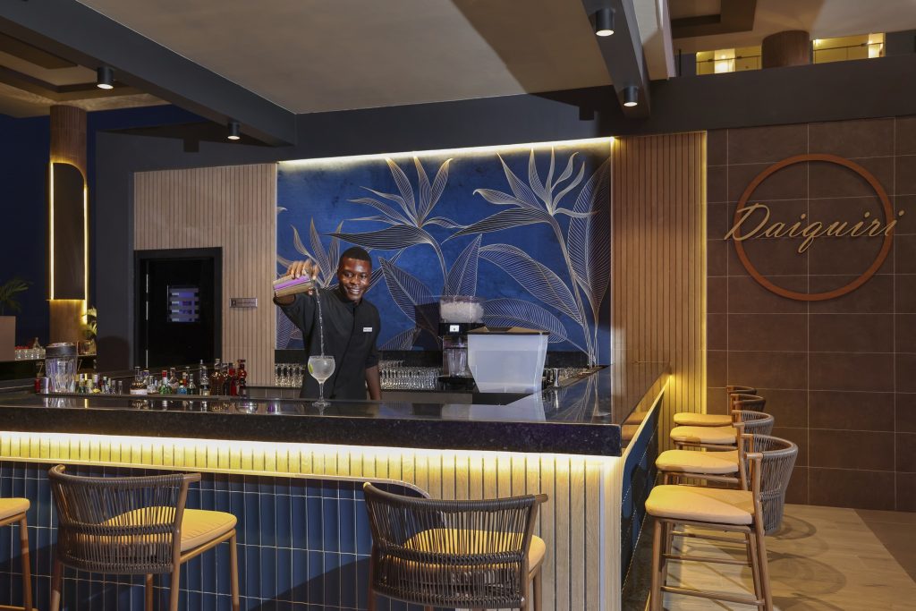 Bar im Hotel Riu Palace Swahili mit dunkler Theke, Barkeeper, Barhockern und blau-goldenem Wandbild