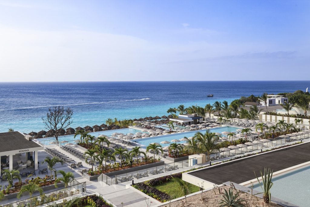 Weitläufige Resort Hotel Riu Palace Swahili mit mehreren Pools und Sonnenschirmen vor tropischem Meer in Sansibar