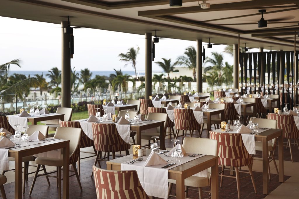 Terrasse des Restaurants main im Hotel Riu Palace Swahili mit gedeckten Tischen, Säulen und Meerblick in Sansibar