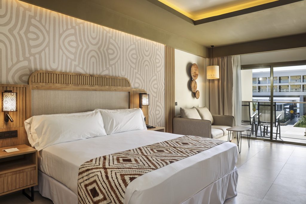 Modernes Hotelzimmer Junior Suite mit großem Bett, Sofa, Holzelementen und Balkon im Hotel Riu Palace Swahili