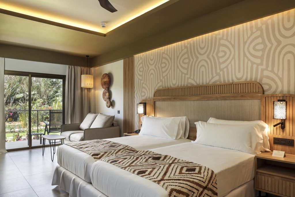 Modernes Hotelzimmer Junior Suite Adapted mit Doppelbett, hellem Holz, Couch und Balkon mit Gartenblick in Sansibar