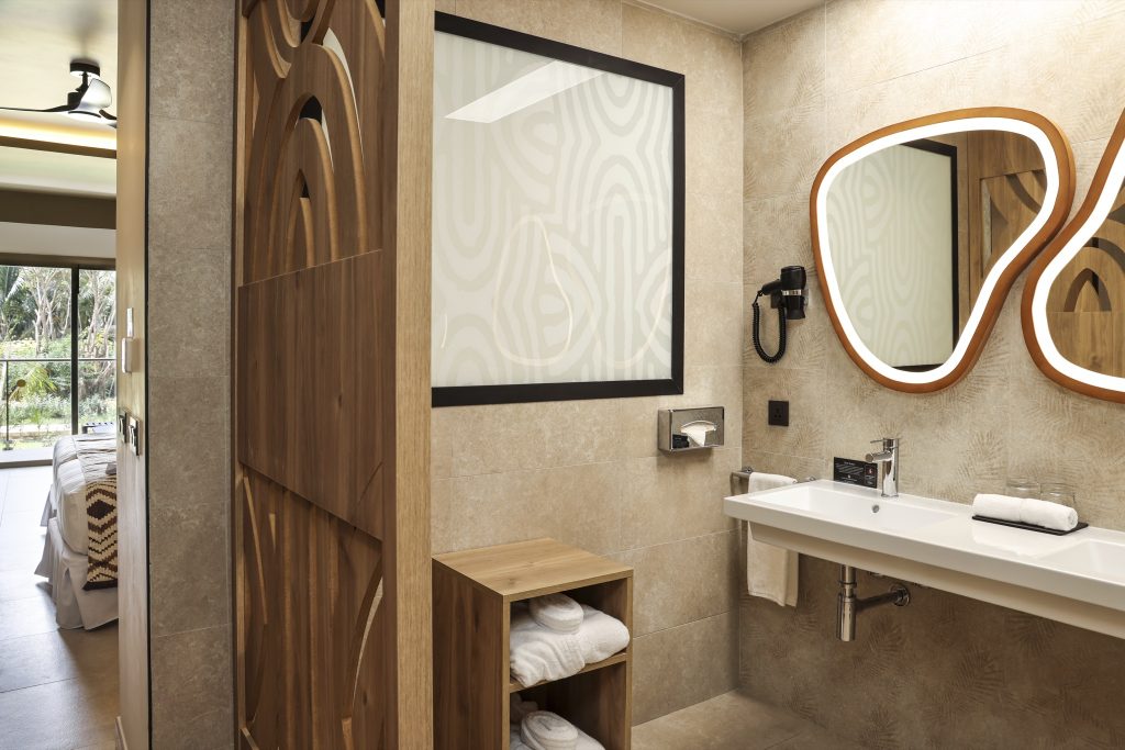 Modernes Badezimmer der Junior Suite Adapted mit Holzregal, großem Spiegel und Außenbereich im Hotel Riu Palace Swahili
