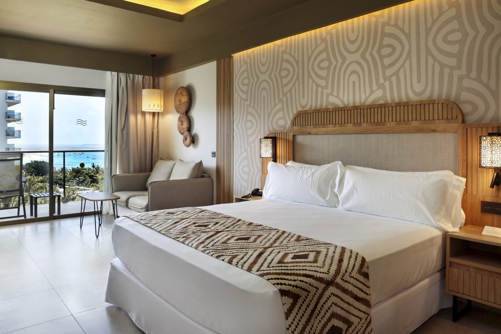 Modernes Hotelzimmer mit großem Bett, geometrischem Stoffmuster, Sitzecke und Meerblick auf Sansibar
