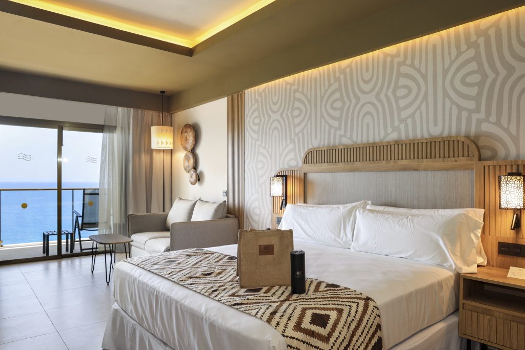 Junior Suite Sea View Elite Club mit großem Bett, Holznachttisch, Sofa und Meerblick im Hotel Riu Palace Swahili