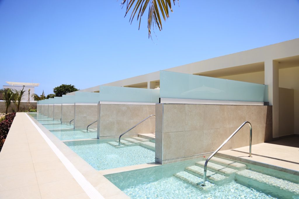 Moderne Hotelzimmer mit privaten Swim-up Pools, klaren Linien, Glas und hellem Stein in Beige und Hellblau