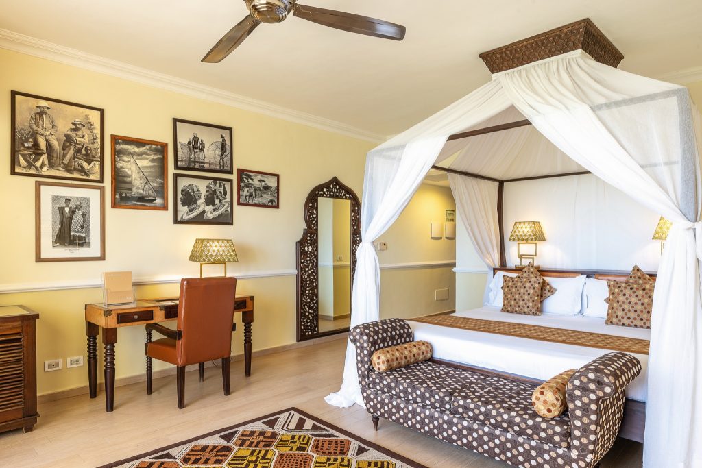 Junior Suite Zimmer im Riu Palace Zanzibar mit Himmelbett, Holzschreibtisch, lederner Sitzgelegenheit und Wanddekoration