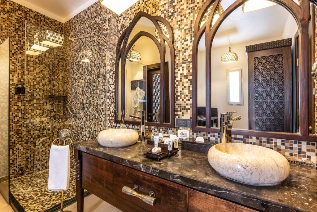 Badezimmer Junior Suite im Riu Palace Zanzibar mit zwei steinernen Waschbecken, Mosaikfliesen und großem Holzspiegel