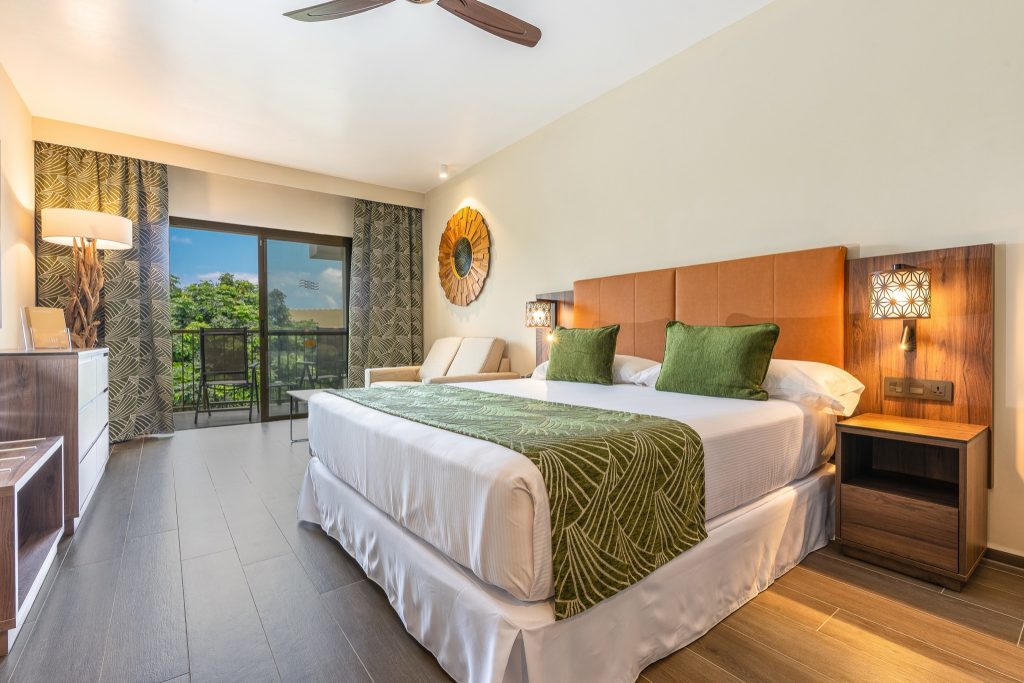Modernes Hotelzimmer Junior Suite Courtyard mit Doppelbett, Holzdetails, Stoffsofa und grünem Ausblick in Sansibar