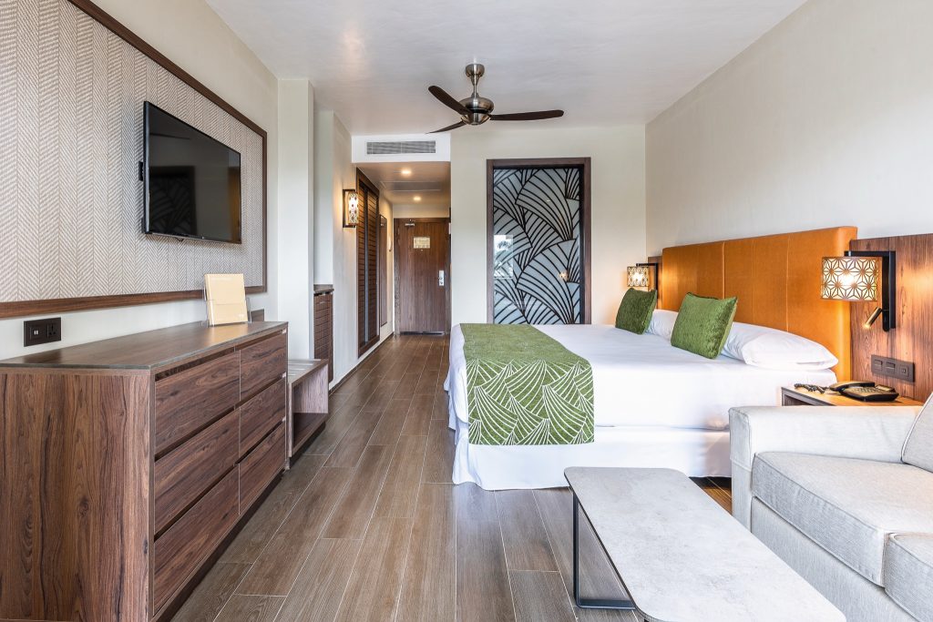 Modernes Hotelzimmer mit Doppelbett, Kommode, Flachbildfernseher und holzähnlichen Fliesen im Riu Palace Zanzibar