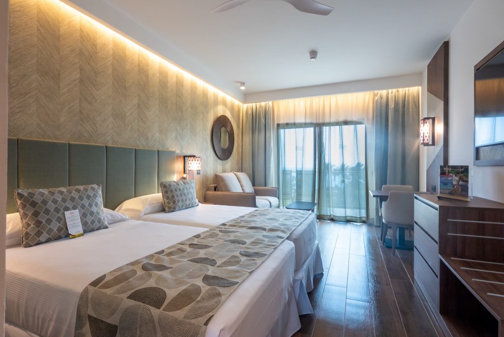 Modernes Hotelzimmer mit Doppelbett, Sitzecke, großem Fernseher und Holzfußboden im Riu Palace Zanzibar