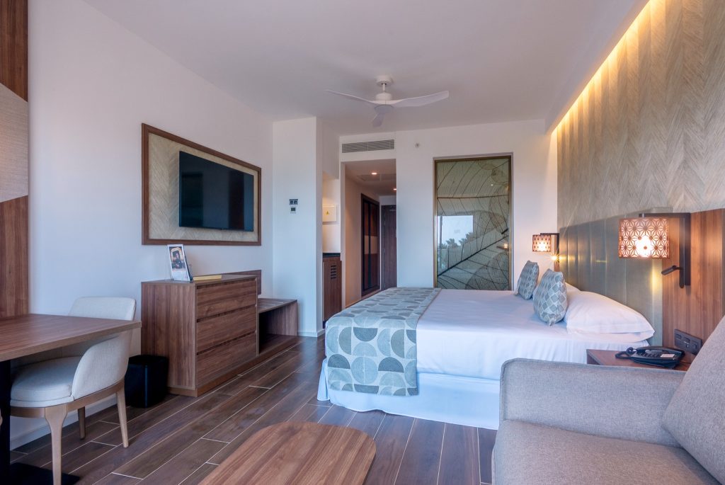 Modernes Hotelzimmer Junior Suite Swim Up mit Doppelbett, Flachbildfernseher, Holzdielen und Tageslicht in Sansibar