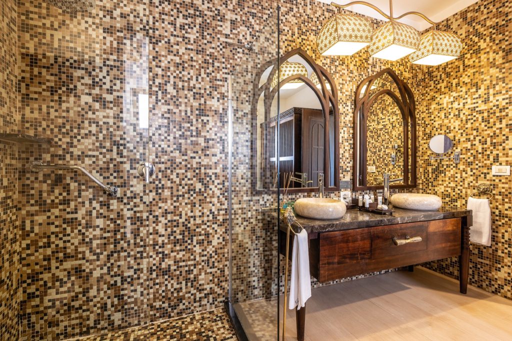 Badezimmer im Riu Palace Zanzibar mit braun-beiger Mosaikfliesenwand, zwei Steinwaschbecken und verzierten Spiegeln