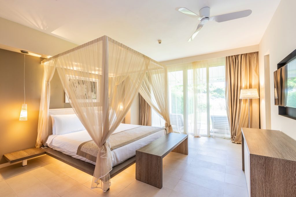 Modernes Hotelzimmer Superior Ocean Suite mit großem Himmelbett, hellen Holztönen und großen Fenstern zum Außenbereich