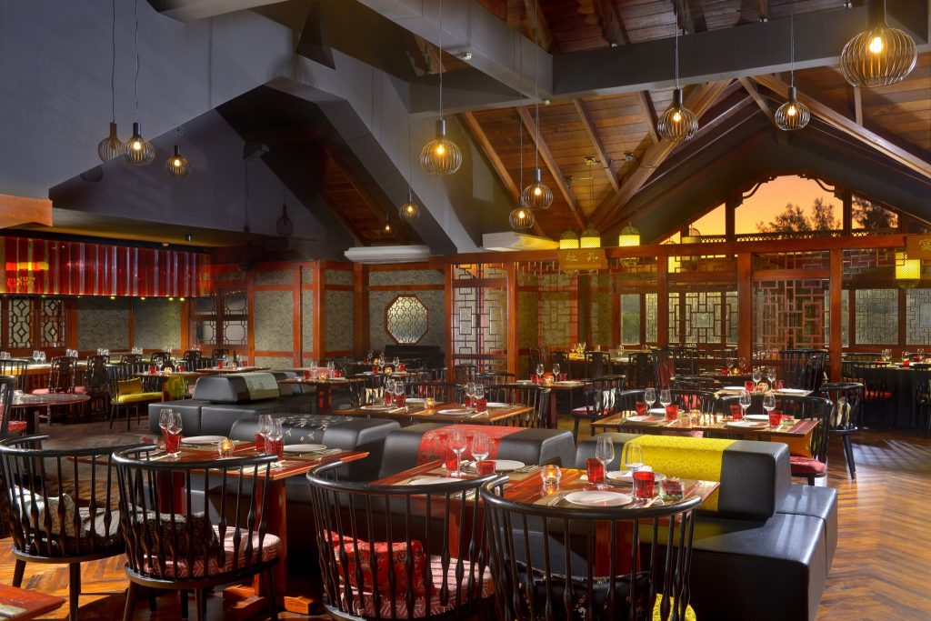 Restaurant Ming Court mit dunklen Holzmöbeln, schwarzen Polstersesseln und großen Fenstern bei Sonnenuntergang