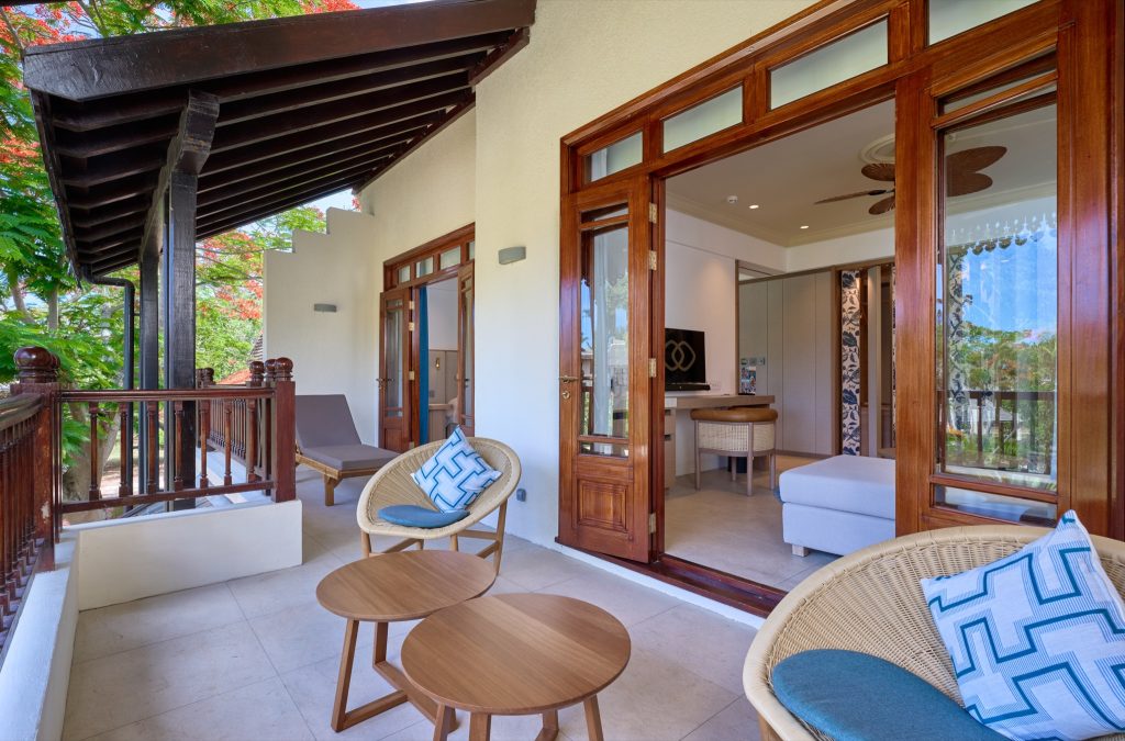 Terrasse mit Holzmöbeln und blauen Kissen, Blick in Family Suite mit hellen Steinwänden und dunklem Holzrahmen