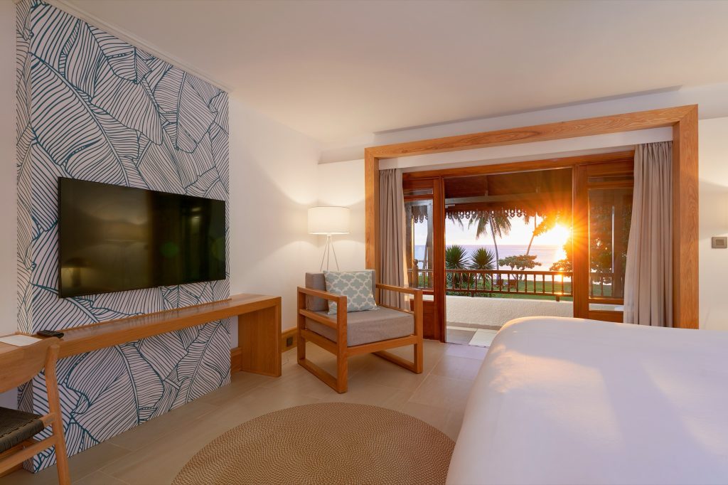 Modernes Hotelzimmer der Imperial Suite mit Flachbildfernseher, Holz- und Stoffelementen sowie Blick auf Terrasse und Meer