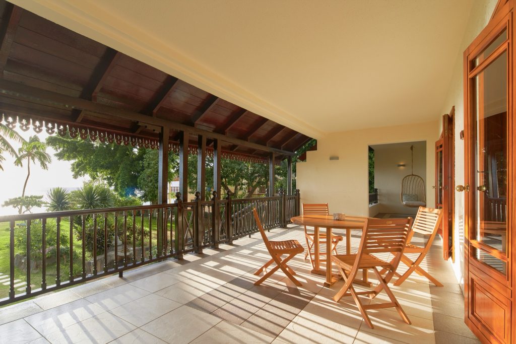 Überdachte Hotelterrasse mit Holzmöbeln und Blick auf üppigen Garten im Sofitel Mauritius L'Impérial Resort & Spa