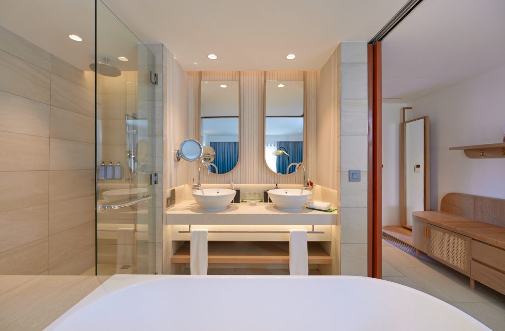 Modernes Badezimmer mit zwei runden Waschbecken, Badewanne und Glasdusche im Sofitel Mauritius L'Impérial Resort & Spa.
